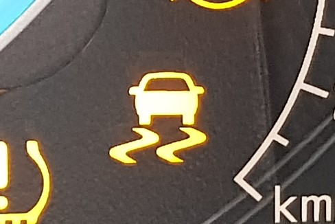 Warning light that looks like a car with skid marks beneath it.